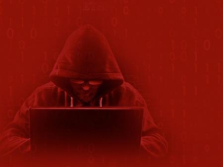 man in a hooded jumper looking at notebook screen against a red background